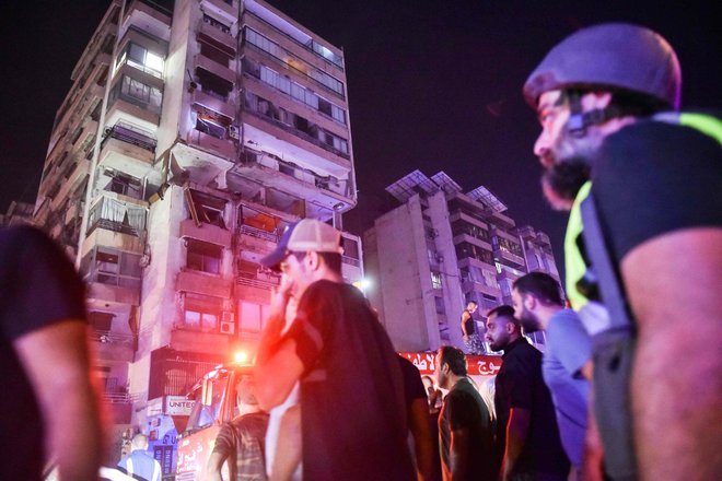 Gasilci pred poškodovanim stanovanjskim blokom FOTO: Fadel Itani/AFP