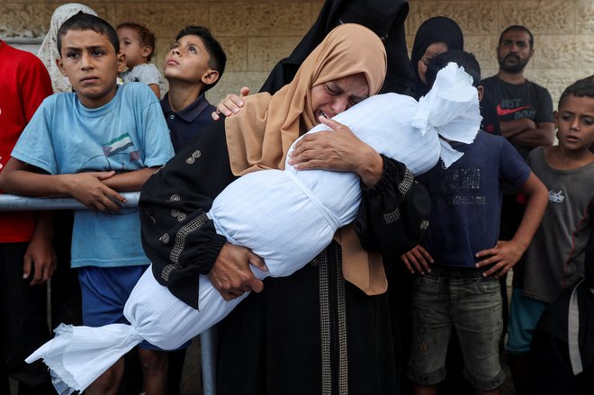 Sorodnica s truplom otroka iz družine al-Durrah, ubitem v izraelskem napadu v Deir Al-Balahu. FOTO: Ramadan Abed/Reuters