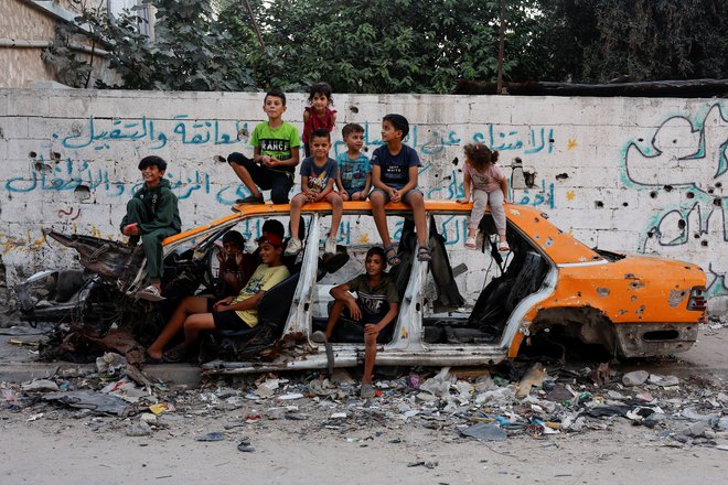 Palestinski otroci pri uničenem avtomobilu v Han Junisu FOTO: Mohammed Salem/Reuters