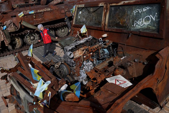 V Kijevu so sinoči sestrelili 15 ruskih brezpilotnikov. Na fotografiji otrok v Kijevu poleg uničenega ruskega tanka na dan branilcev. FOTO: Anatolii Stepano/AFP