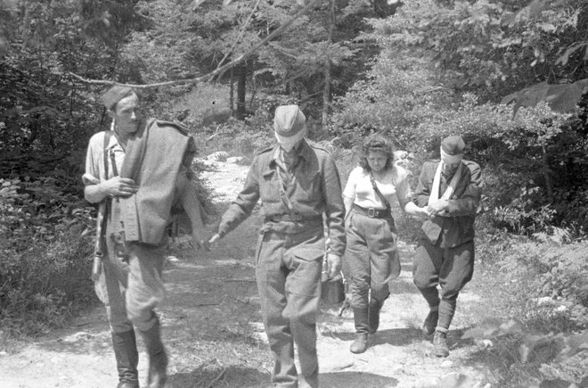 Bolničar in bolničarka vodita ozdravela ranjenca z zavezanimi očmi iz bolnice do javke, od koder se bosta vrnila v enoto; poletje 1944. FOTO: Janez Milčinski, hrani Muzej novejše zgodovine Slovenije