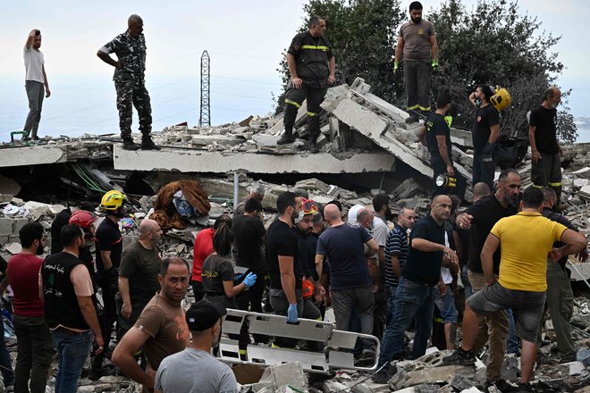 Ljudje si ogledujejo škodo na prizorišču letalskega napada izraelske vojske v vasi Majsra v libanonskem gorovju. FOTO: Joseph Eid/AFP