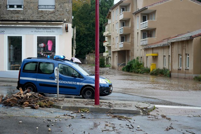 Policijsko vozilo pred poplavljeno ulico v vasi Bourg-Argental 17. oktobra 2024, potem ko je močno deževje prizadelo departmaje Haute-Loire, Ardeche, Rhone in Loire v francoski južni osrednji Franciji. FOTO: Sylvain Thizy/AFP