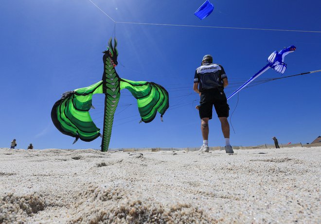 Američan Tony Jetland drži vrvico svojega zmaja na plaži Dolphin Beach na 30. mednarodnem festivalu zmajev v Cape Townu, ki je ta konec tedna potekal v okviru kampanje ozaveščanja o svetovnem dnevu duševnega zdravja. Na festivalu so ljubitelji zmajev spuščali pisane zmaje in zbirali sredstva za podporo duševnemu zdravju. Foto: Esa Alexander/Reuters