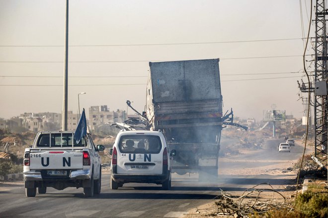 Vozila Združenih narodov spremljajo uničen tovornjak, ki naj bi ga uporabljali delavci Agencije ZN za pomoč in zaposlovanje palestinskih beguncev (UNRWA), na katerega so pred tem streljale izraelske sile. FOTO: Eyad Baba/AFP