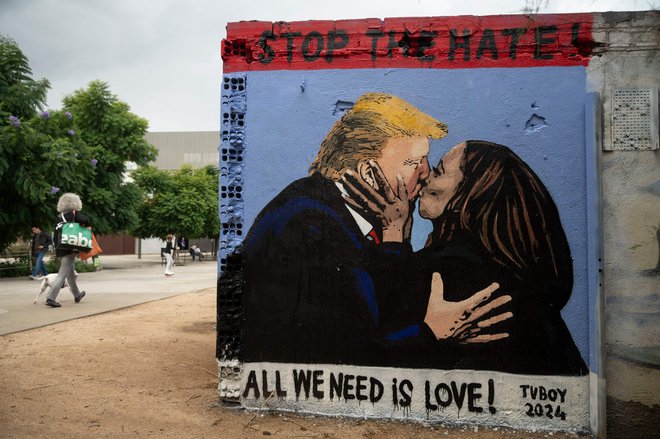 Grafit urbanega umetnika TV Boya v Barceloni, na katerem se glavna kandidata Donald Trump in Kamala Harris poljubljata. V razumevanju bi bil svet lepši. FOTO: Josep Lago/AFP