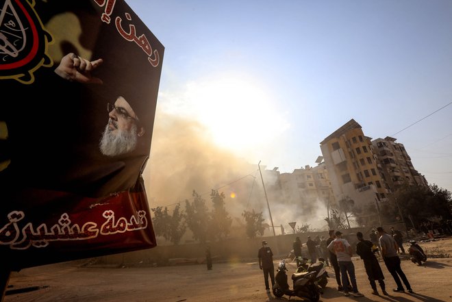 Poster ubitega voditelja Hezbolaha ob svežih ruševinah zaradi izraelskega napada na obrobju Bejruta. FOTO: AFP