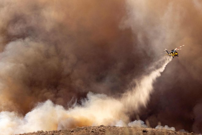 Tudi s helikopterji se z ognjem bori več sto gasilcev. FOTO: Etienne Laurent/AFP