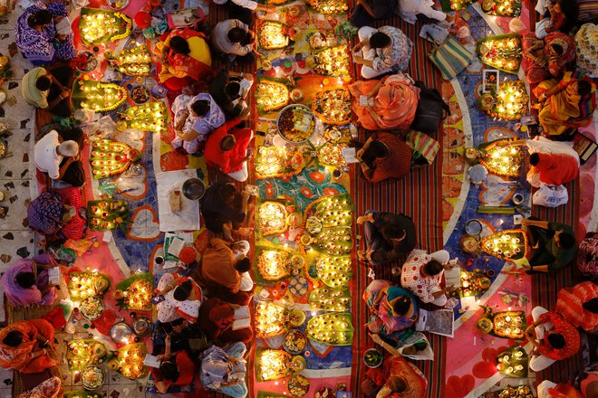 Hindujski verniki sedijo med oljnimi svetilkami in svečami v templju v Daki ter molijo k hindujskemu svetniku in filozofu med praznovanjem festivala Rakher Upobash. Foto: Mohammad Ponir Hossain/Reuters