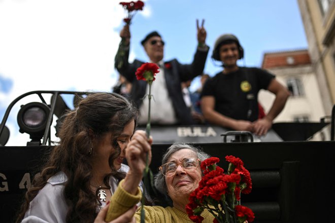 Celeste Caeiro (na fotografiji spodaj desno) je nageljne podarila vojakom, ki so jih vstavili v cevi pušk. FOTO: Patricia De Melo Moreira/AFP