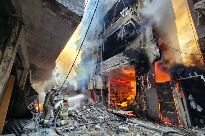 Gasilci v boju z ognjem po današnjem izraelskem napadu na jugu Bejruta. FOTO: AFP