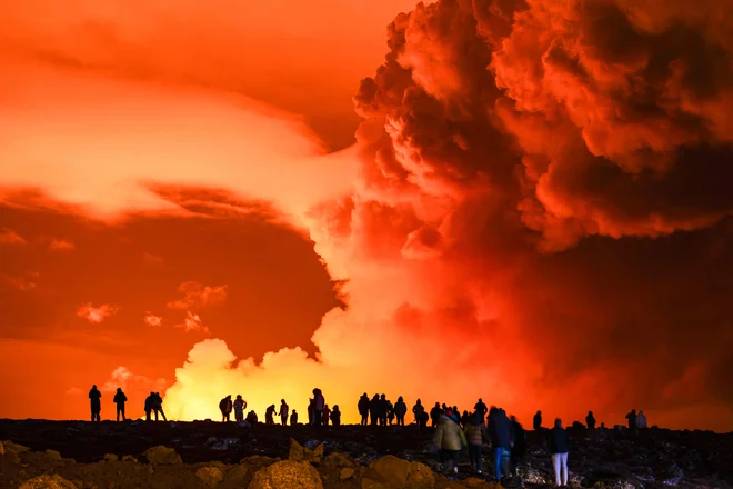 Ljudje so se marca zbrali, da bi opazovali, kako lava teče iz razpoke na polotoku Reykjanes. FOTO: Ael Kermarec/AFP