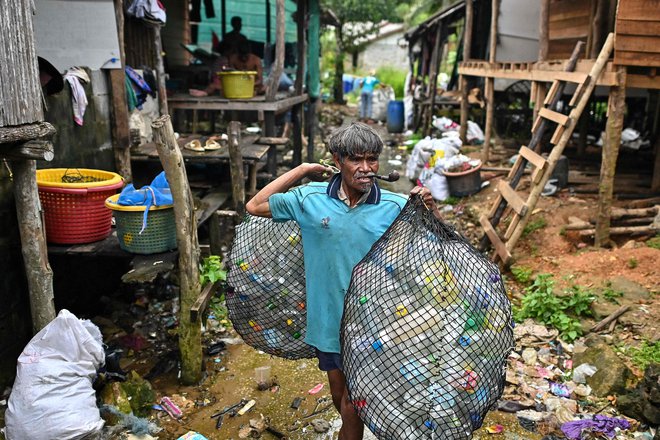 Rribič Moken v svoji ribiški vasi na južnem tajskem otoku Koh Chang nosi vreče plastičnih odpadkov, ki jih prodaja uslužbencem podjetja Tide. Družba Tide, ki je bila ustanovljena leta 2019, letno zbere približno 1.000 ton plastike na Tajskem in drugih lokacijah. Zbrano plastiko predela v pelete, preden jo pošlje strankam, kot je skupina Condor, eden največjih evropskih proizvajalcev preprog. Foto: Manan Vatsyayana/Afp