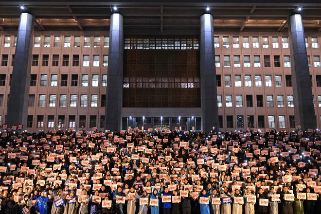 Množice protestnikov so prebedele noč s svečami in transparenti v rokah z zahtevo, naj predsednik Jun Sok Jol nemudoma odstopi. FOTO: Jung Yeon-je/AFP