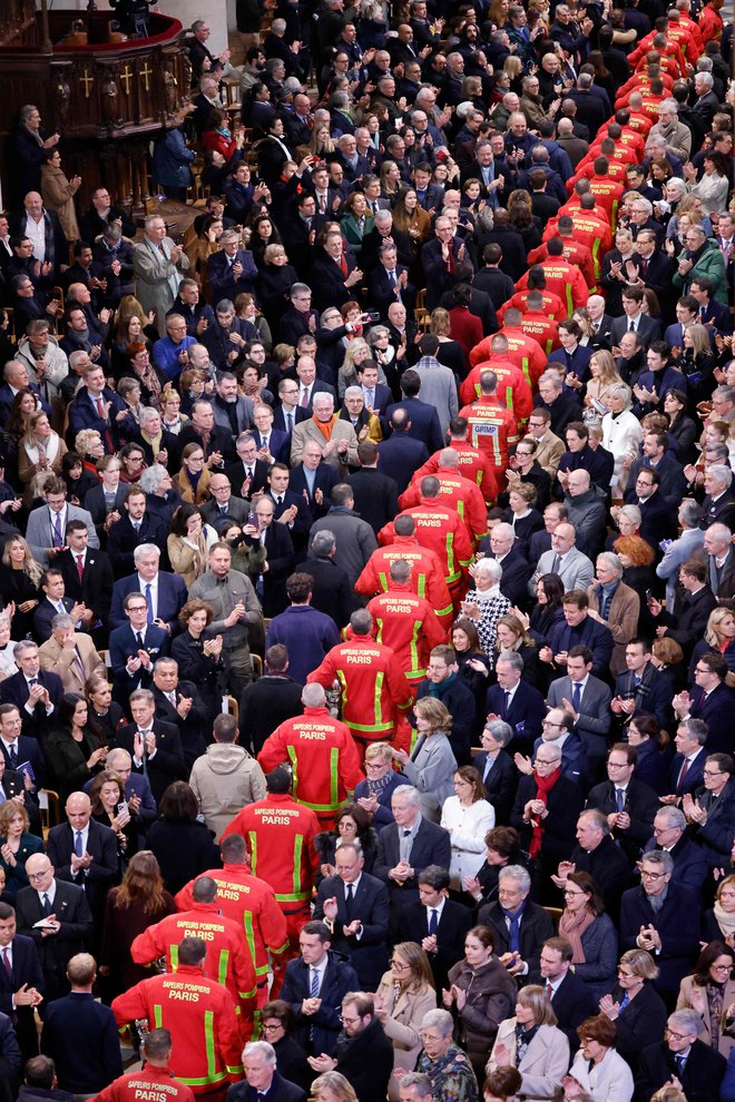 Gasilci, reševalci in gradbeniki, ki sodelujejo pri obnovi katedrale Notre-Dame, paradirajo med slovesnostjo ob ponovnem odprtju znamenite katedrale. FOTO: Ludovic Marin/Afp