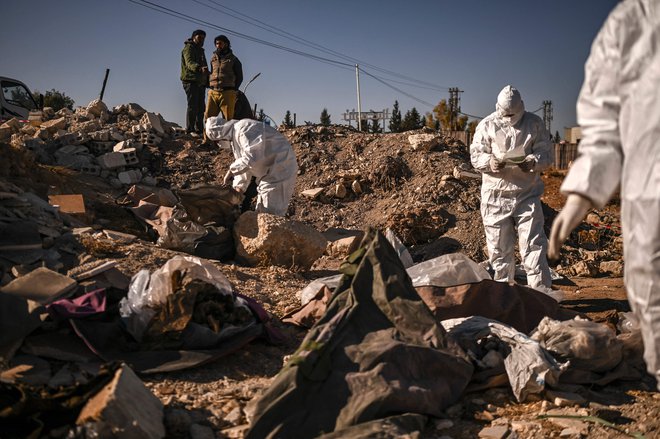 Člani sirske civilne zaščite Bele čelade v Damasku zbirajo človeške ostanke v odkritem množičnem grobišču. Foto: Aris Messinis/Afp