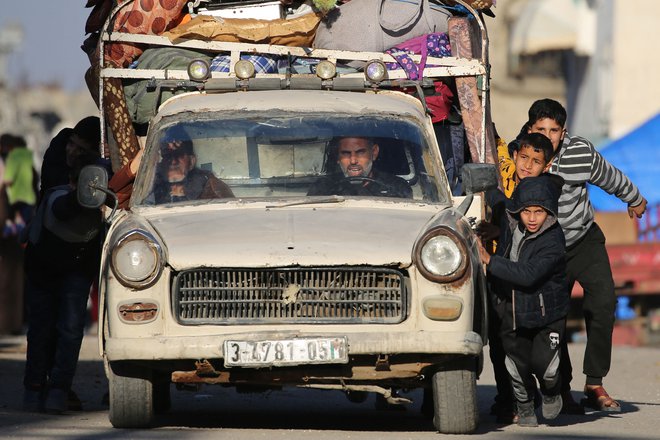 Palestinski otroci pomagajo potiskati avto, ko se bili ljudje po prejemu ukaza izraelske vojske primorani seliti iz svojih domov s svojim premoženjem v begunskem taborišču Bureij v osrednjem delu Gaze. Foto: Eyad Baba/Afp