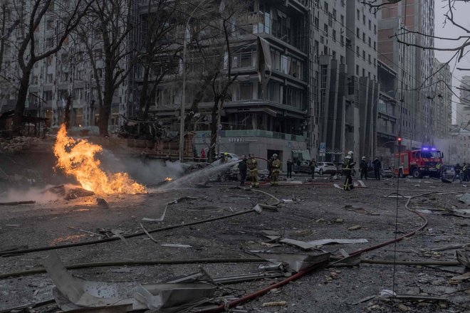 Ukrajinski gasilci poskušajo pogasiti požar na mestu ruskega raketnega napada v Kijevu. FOTO: Roman Pilipey/AFP