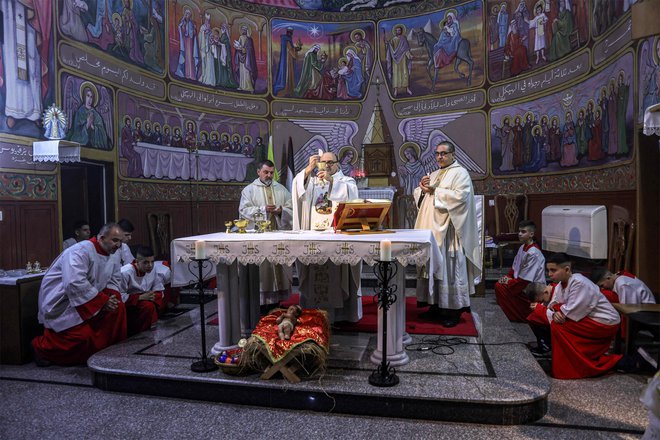 Oče Gabriel Romanelli, župnik rimskokatoliške cerkve Svete družine, med mašo na božični večer v cerkvi v soseski Zaytoun v mestu Gaza. FOTO: Omar Al-qattaa/AFP