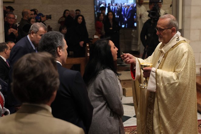 Latinski patriarh Jeruzalema Pierbattista Pizzaballa deli obhajilo med božično polnočno mašo v katoliški cerkvi svete Katarine v svetopisemskem mestu Betlehem na okupiranem Zahodnem bregu. FOTO: Alaa Badarneh/AFP