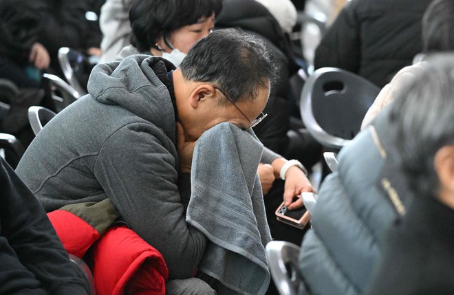 Na letališču Muan so se zbrali svojci žrtev in v solzah trepetali, ko so oblasti glasno prebirale imena umrlih. FOTO: Jung Yeon-je/AFP