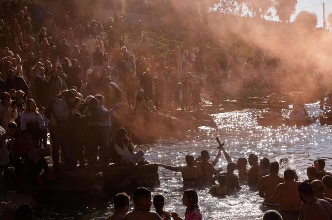 Grški pravoslavni verniki držijo lesen križ med tradicionalnim obredom velikega blagoslova vode za pravoslavni dan Gospodovega razglašenja v Pireju pri Atenah. Foto: Angelos Tzortzinis/Afp