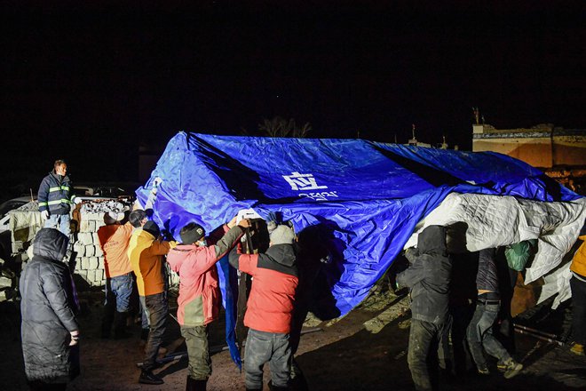 Reševalci si prav tako prizadevajo čim prej postaviti dovolj šotorov za evakuirane prebivalce, saj se bo temperatura po napovedih še spustila. FOTO: AFP