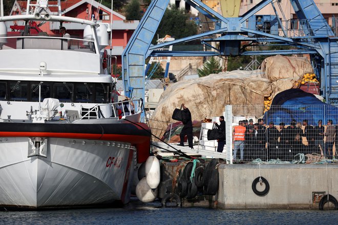 Migranti, ki so jih pridržali v sprejemni postaji v Albaniji, se vkrcavajo na plovilo italijanske obalne straže, da bi odpluli v Italijo, potem ko je sodišče v Rimu razveljavilo njihove odredbe o pridržanju. FOTO: Florion Goga/Reuters