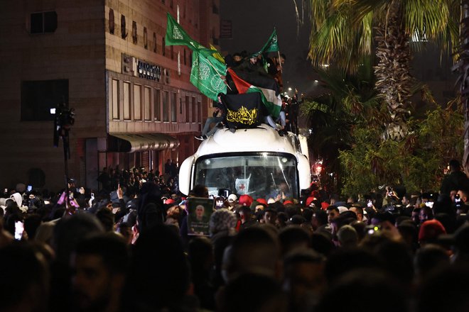 Mladi Palestinci so splezali na avtobus, ki je prevažal izpuščene zapornike, in vihrali s palestinsko, Hamasovo in Hezbolahovo zastavo. FOTO: Zain Jaafar/AFP