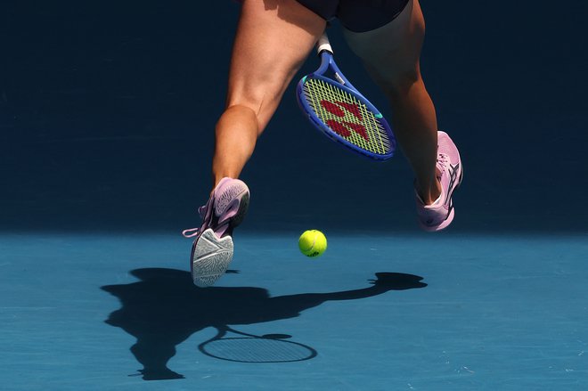 Švicarka Belinda Bencic vrača žogico med nogami proti Američanki Coco Gauff med ženskim dvobojem posameznic  na osmi dan odprtega teniškega prvenstva Avstralije v Melbournu. Foto: David Gray/Afp