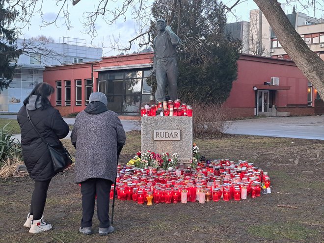 Občani so že dan po nesreči začeli k spomeniku rudarja na Titovem trgu prinašati cvetje in sveče. FOTO: Špela Kuralt/Delo