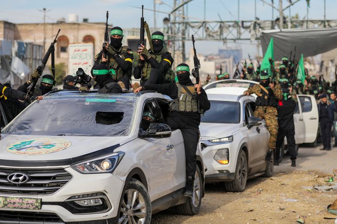 Na desetine uniformiranih in zamaskiranih borcev Hamasa z orožjem in zastavami se je zbralo na mestu predaje. FOTO: Dawoud Abu Alkas/Reuters