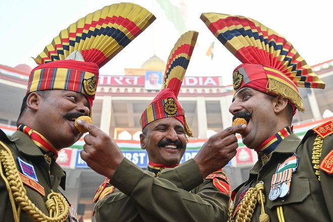 Vojaki indijskih obmejnih varnostnih sil (BSF) si ponujajo sladkarije med praznovanjem dneva republike na indijsko-pakistanskem mejnem prehodu Wagah, približno 35 km od Amritsarja. Foto: Narinder Nanu/Afp