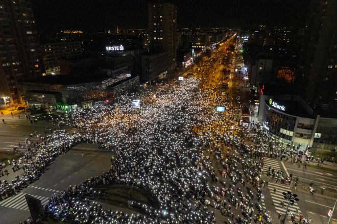 Nočna fotografija množice med 15 minutnim spominom na 15 umrlih v nesreči pred novosadsko železniško postajo napoveduje, da bo današnje zaprtje treh mostov dodgodek, ki bi ga oblast najraje spregledala. FOTO: Nenad Mihajlovic Afp