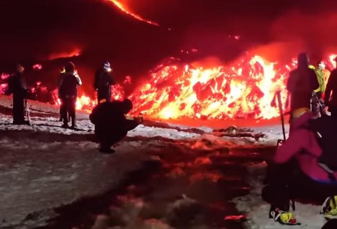 Nad čudom narave očarani obiskovalci vulkana Etna tik ob vrelem potoku, ki je nastal po eksploziji. FOTO: posnetek zaslona/facebook