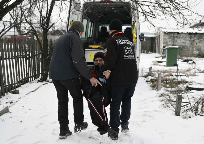 Moška evakuirata 73-letnega Volodimirja v vozilo dobrodelne fundacije East SOS iz njegove hiše v vasi Černigivka blizu frontnega mesta Pokrovsk v regiji Doneck. Foto: Genya Savilov/Afp