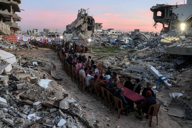 Paelestinci se zbirajo ob ruševinah uničenih stavb, kjer se 2. marca na skupnem obroku iftar na drugi dan muslimanskega svetega meseca ramadan v okrožju Tal al-Hawa v Gazi. Foto: Omar Al-qattaa/Afp