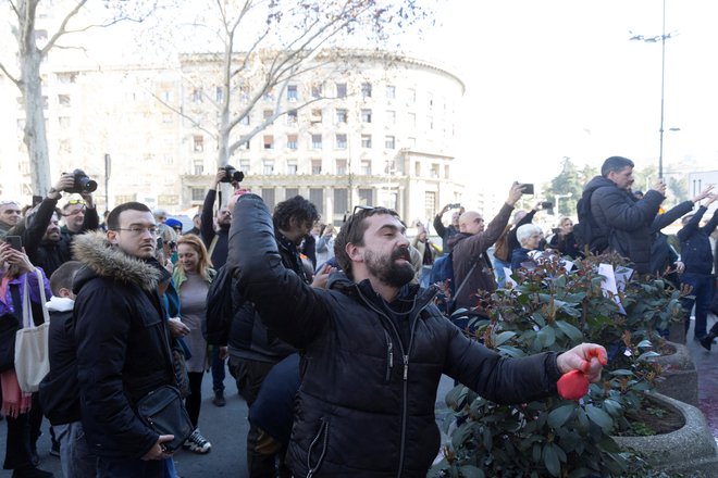 Protestniki mestno hišo v Beogradu obmetavajo z rdečo barvo. FOTO: Djordje Kojadinovic/Reuters