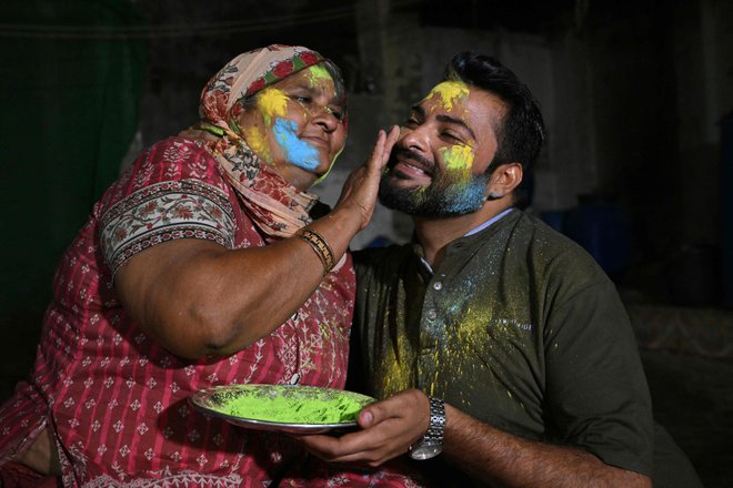 Mati barva obraz svojega sina ob praznovanju hindujskega praznika Holi v puščavskem mestu Mithi na jugovzhodu Pakistana. V pakistansikem puščavskem mestu hindujci pripravljajo obroke za muslimane, ki se postijo, ti pa se zberejo, da bi pozdravili procesijo ob prazniku Holi, kar je redek trenutek verske solidarnosti v tej islamski državi. Foto: Asif Hassan/Afp